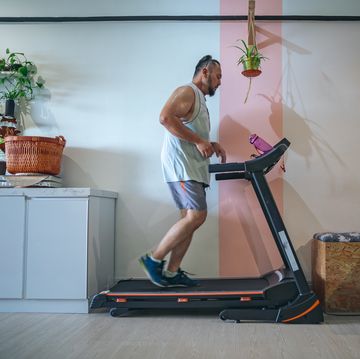 profile shot of a bearded matured man running on a treadmill at home