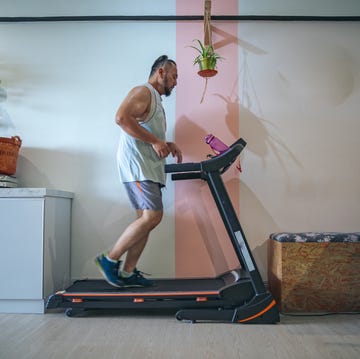 profile shot of a bearded matured man running on a treadmill at home