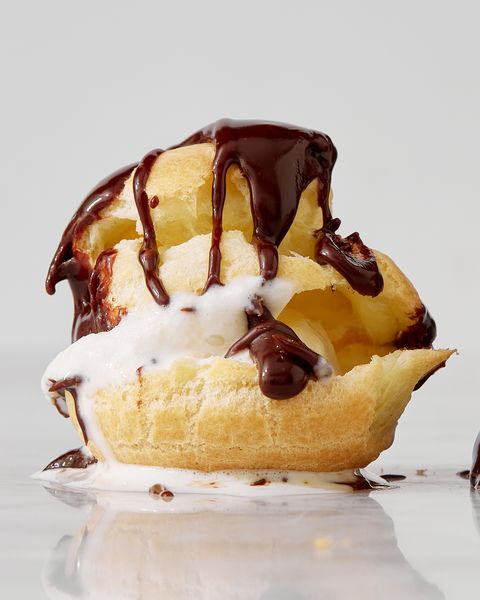 closeup of an ice cream filled profiterole topped with chocolate sauce