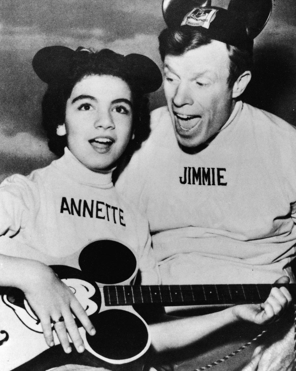 annette funicello plays guitar and sings with jimmie dodd, both wear tops with their names embroidered on them and mickey mouse ear hats