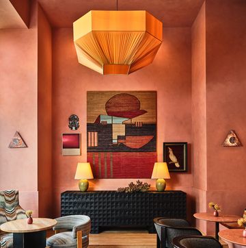a restaurant with a pink and terracotta color palette and art hanging on the walls
