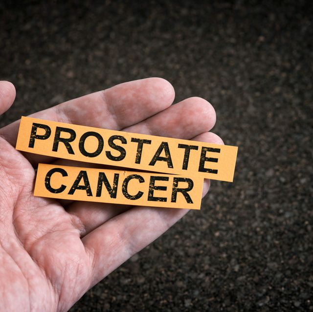 a man holding yellow pieces of paper with the words prostate cancer on them in his hand close up