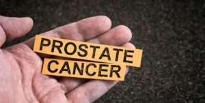 a man holding yellow pieces of paper with the words prostate cancer on them in his hand close up