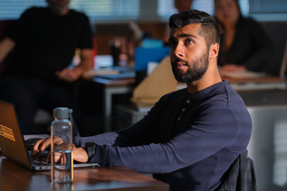 Individual working on a laptop at a desk with a water bottle nearby