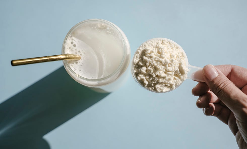 protein isolate powder unflavored whey protein in measuring scoop and drinking glass in bright sunlight