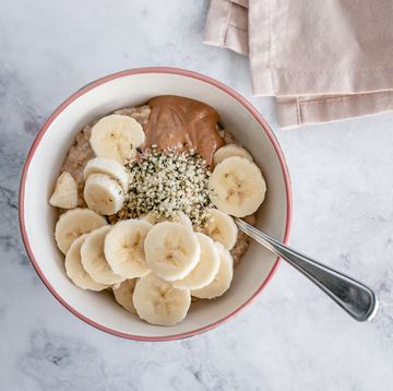protein porridge, overhead view of a bowl of oatmeal with slices of banana, nut butter and hemp seeds