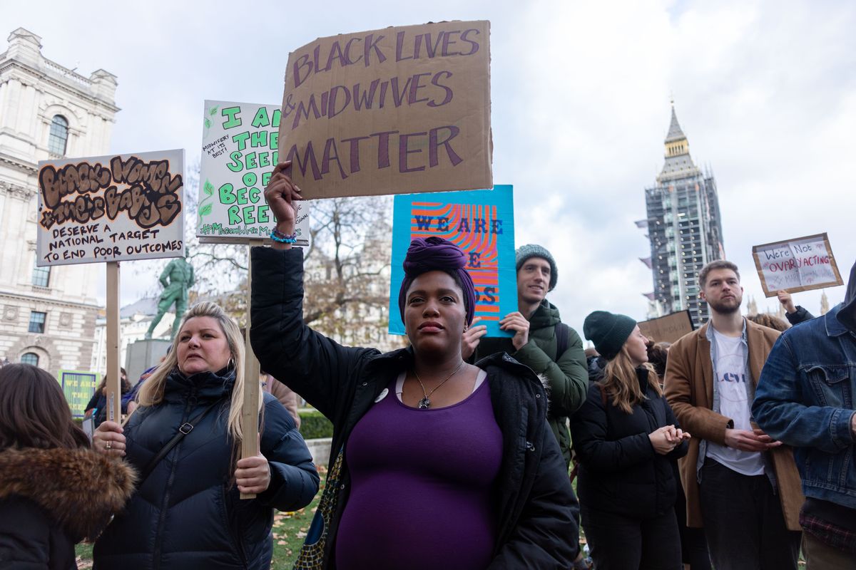 a protester holds a placard that reads 'black lives midwives matter