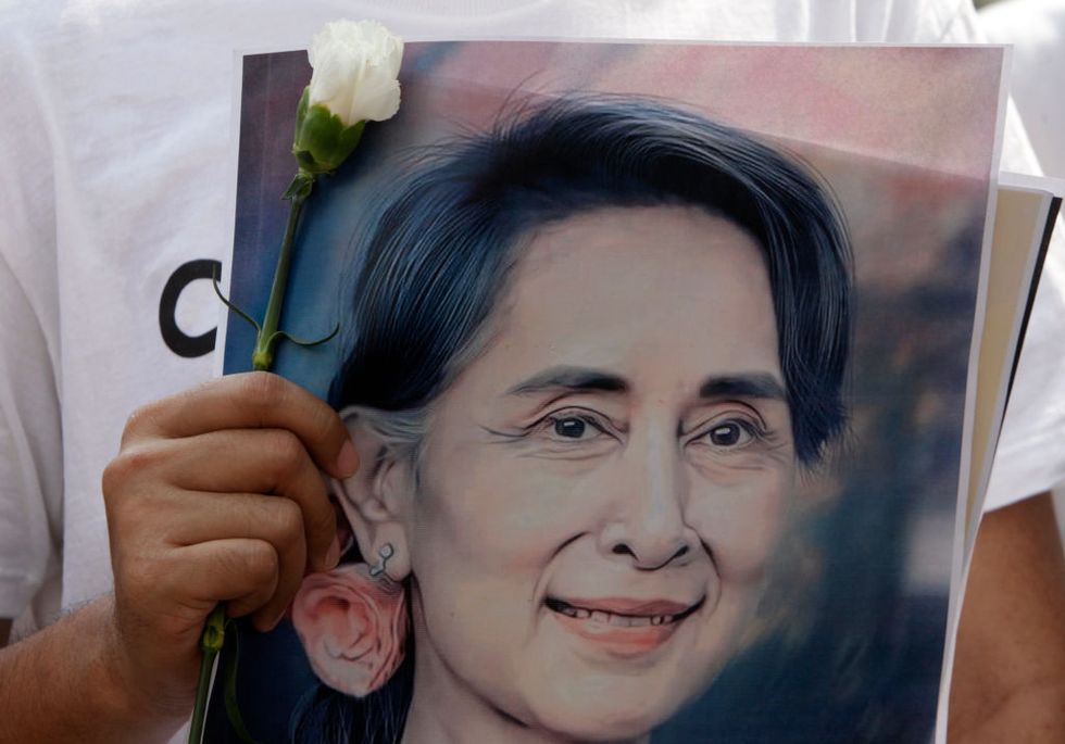 a protester holds a portrait of aung san suu kyi during a