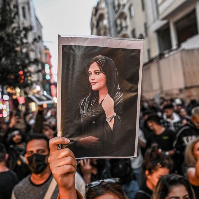 a group of protestors with someone holding up a photo of mahsa amini