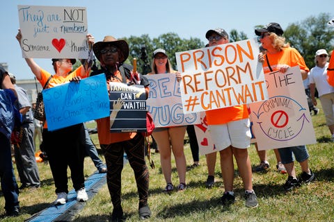 protestors holding signs that read prison reform can't wait and families can't wait