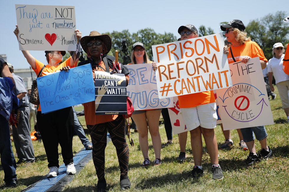 protestors holding signs that read prison reform can't wait and families can't wait