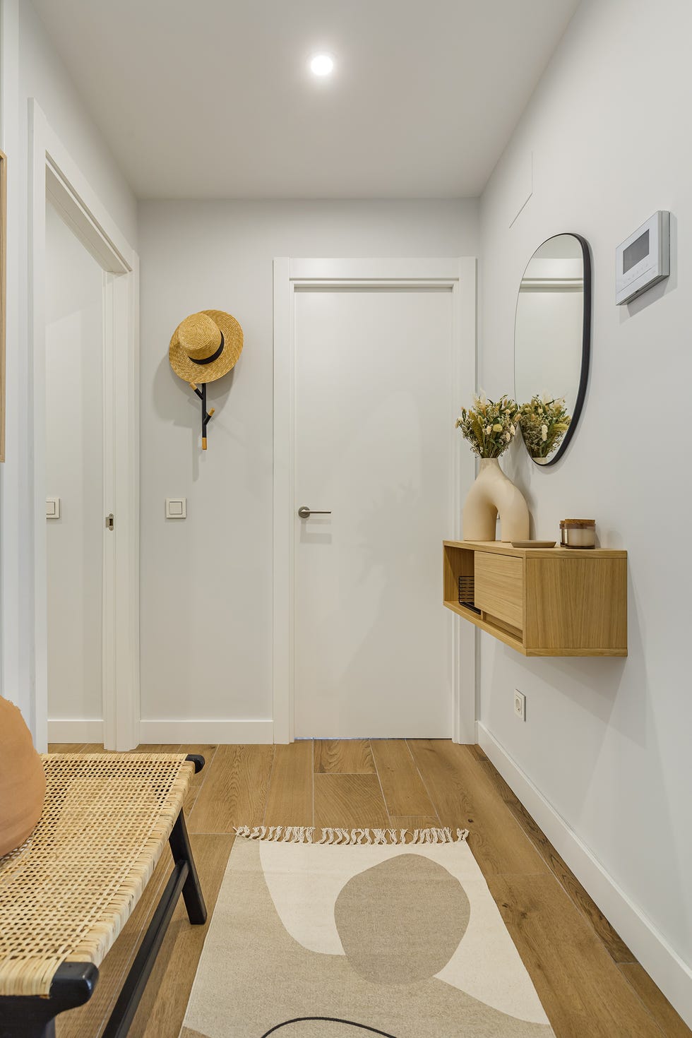 recibidor con consola de madera volada y espejo con forma orgánica