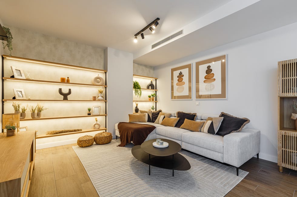 salón con sofá gris, mesas nido negras y estantería de madera a medida