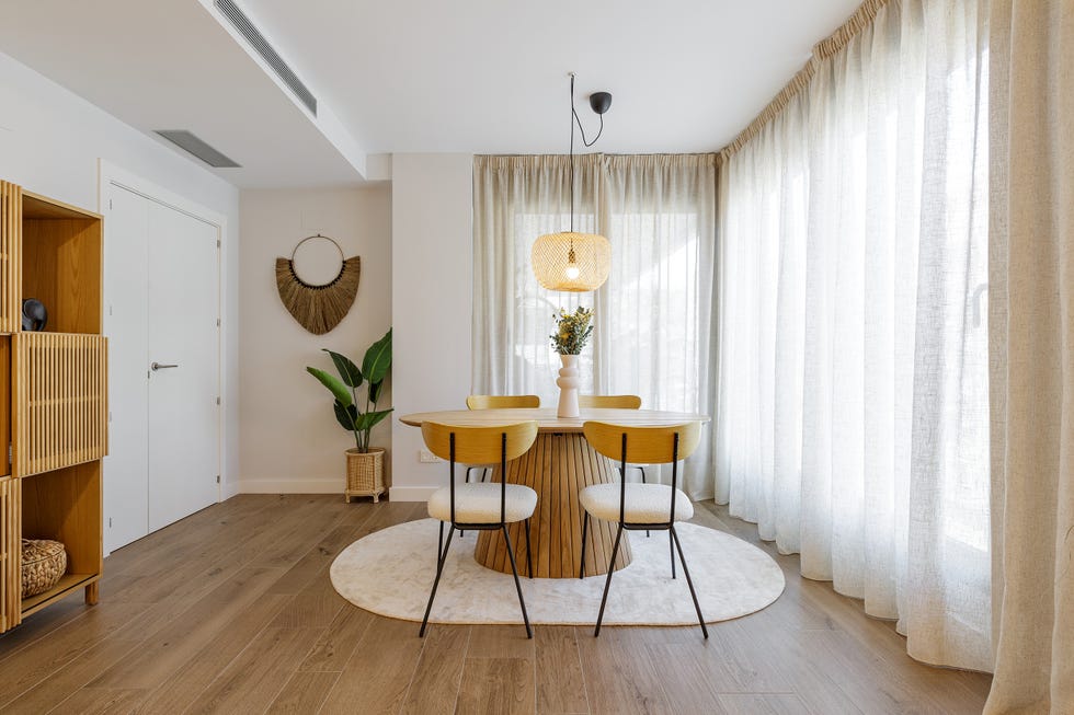 mesa de comedor de madera redonda con sillas a juego, lámpara de fibras y alfombra en color beige