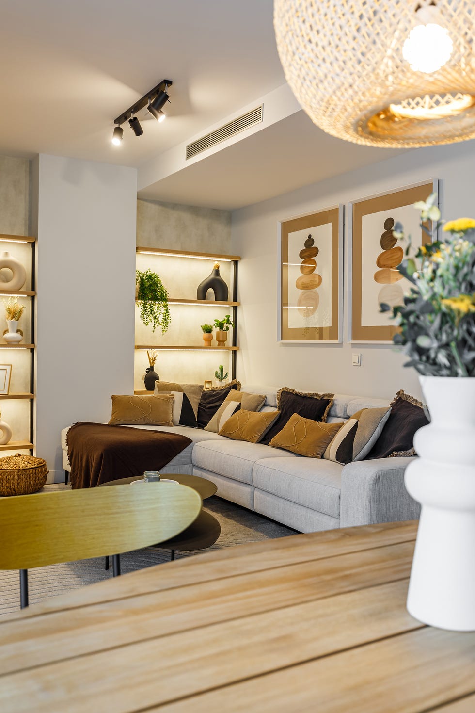 salón con sofá gris, mesas nido negras y estantería de madera a medida