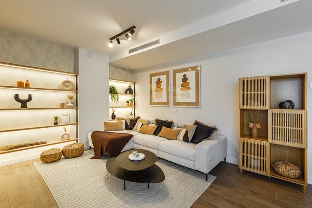 salón con sofá gris, mesas nido negras, estantería de madera y estantería a medida con iluminación led