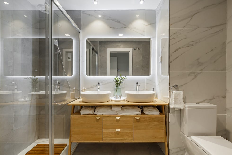 baño con revestimientos de mármol y mueble de madera
