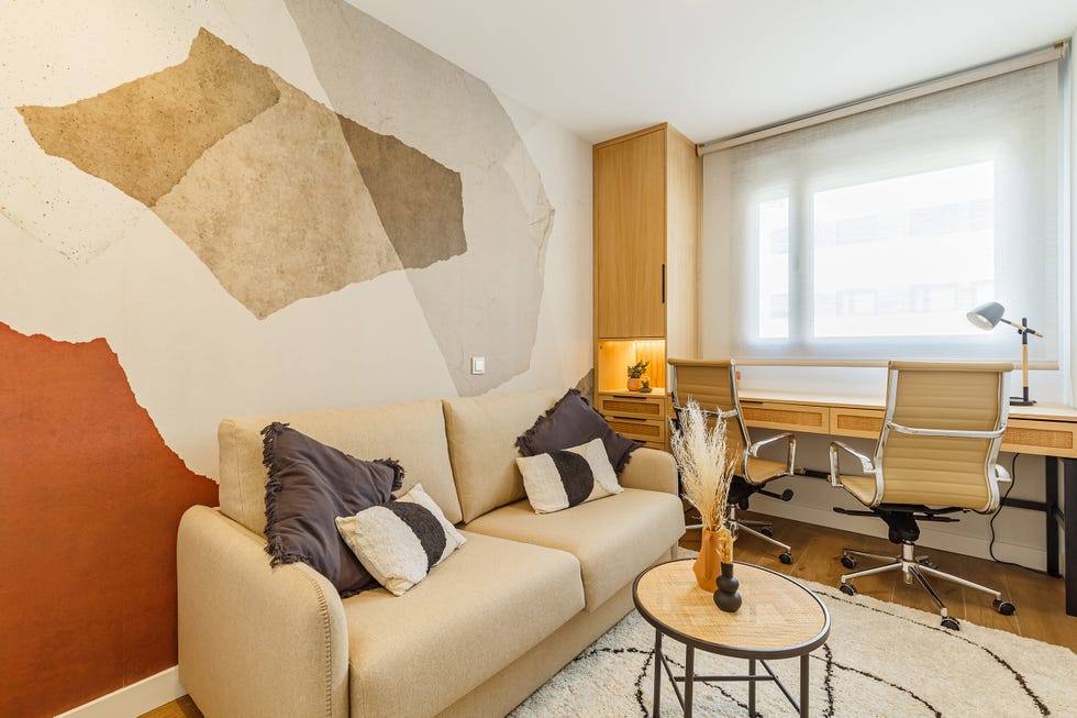 habitación con sofá cama beige y escritorio de madera con dos sillas