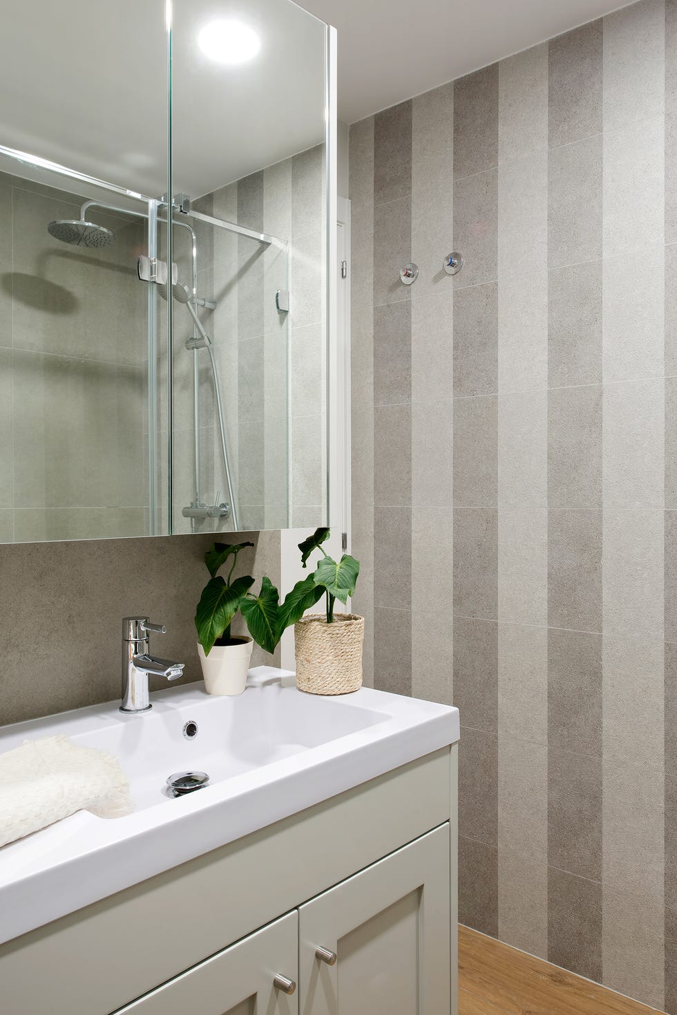 baño con armario de espejos, armario bajo lavabo de color gris y azulejos a rayas grises