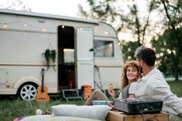 una pareja utiliza un proyector en el lateral de una caravana