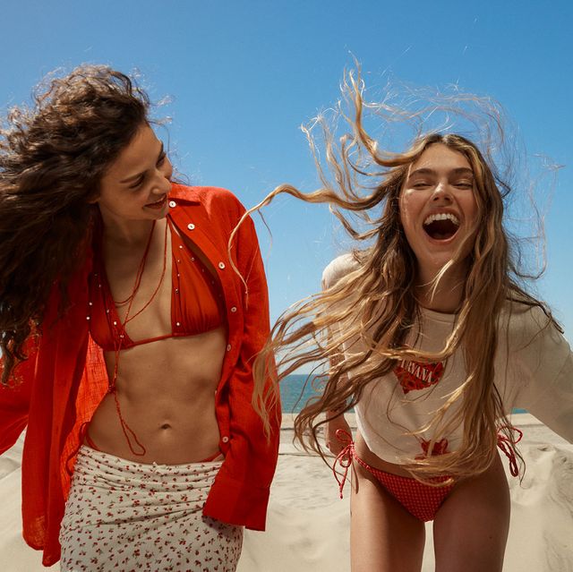 a couple of women in garments laughing on a beach
