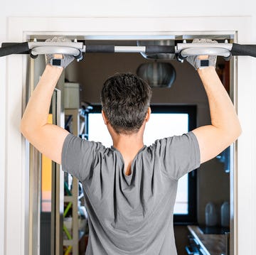 man using pull up bar mounted on door in home