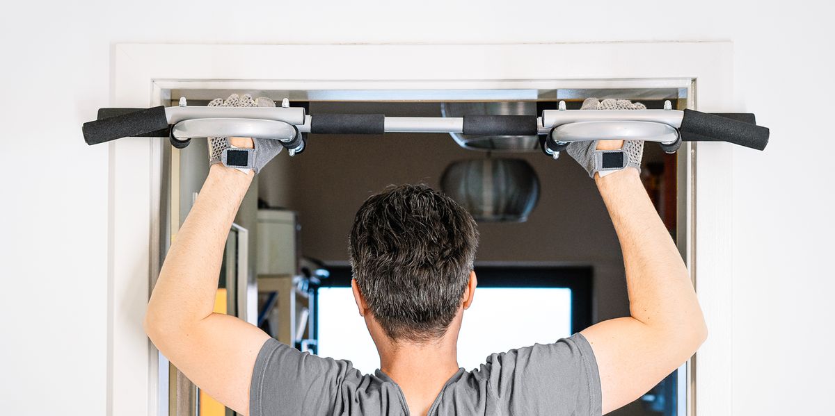 man using pull up bar mounted on door in home