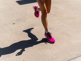 a runners foot makes contact with a sidewalk