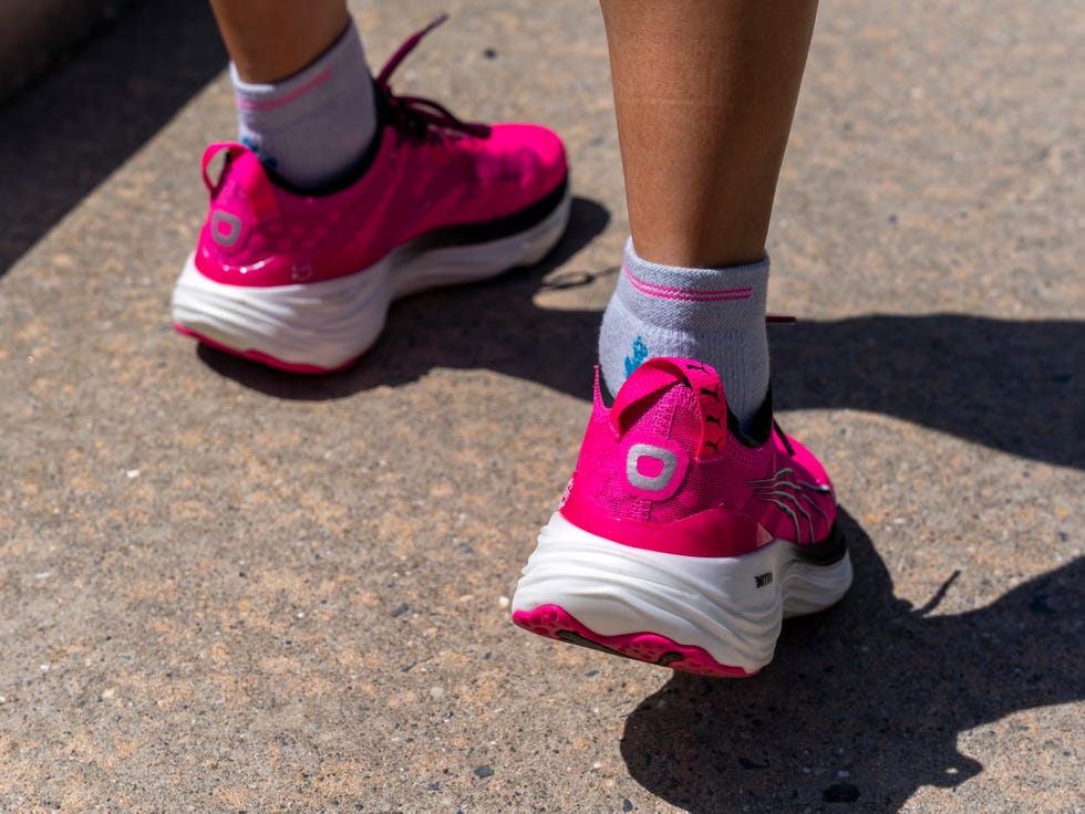 bright pink athletic shoes are worn by an individual, visible from the back