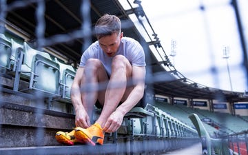 athlete tying shoelaces in stadium seating