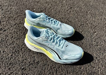a pair of light blue running shoes with a hint of yellow on a pavement