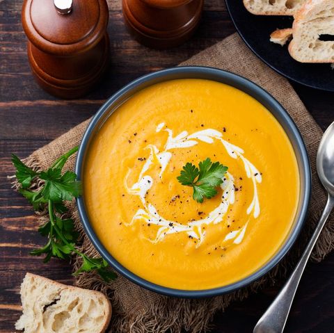 Pumpkin and carrot soup with cream and parsley Top view