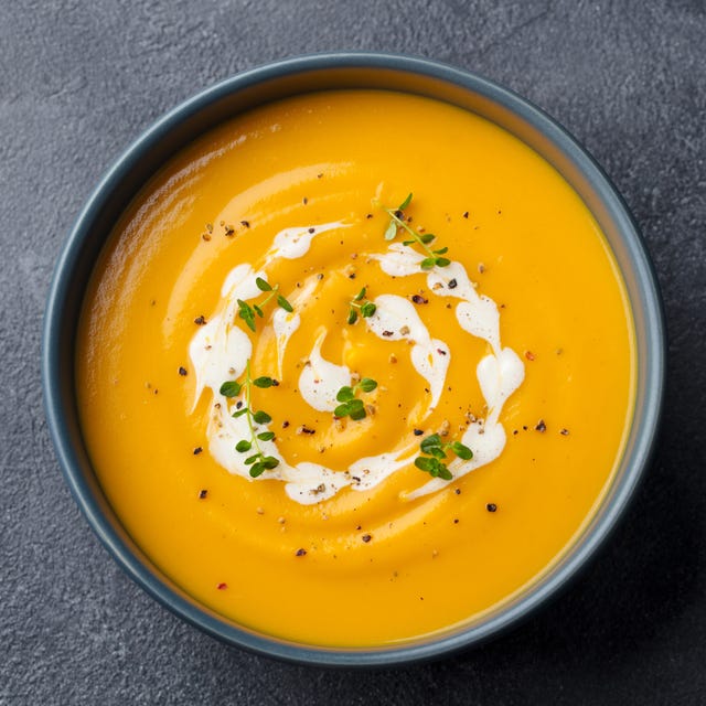 Pumpkin, carrot cream soup in a bowl. Slate background. Close up. Top view
