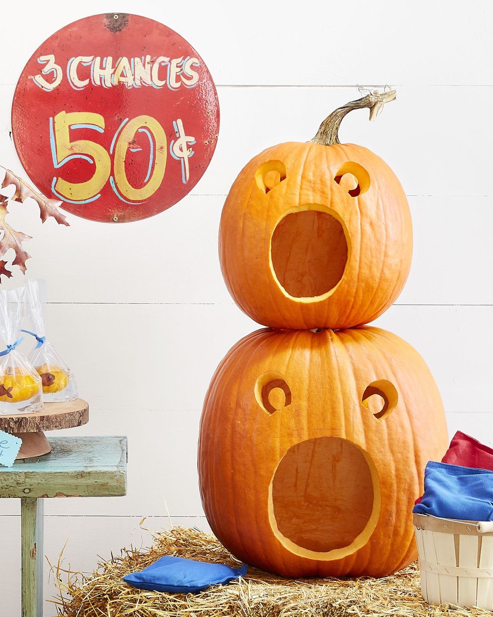two stacked carved pumpkins with wide open mouths for a game of bean bag toss, a sign reads 3 chances 50 cents