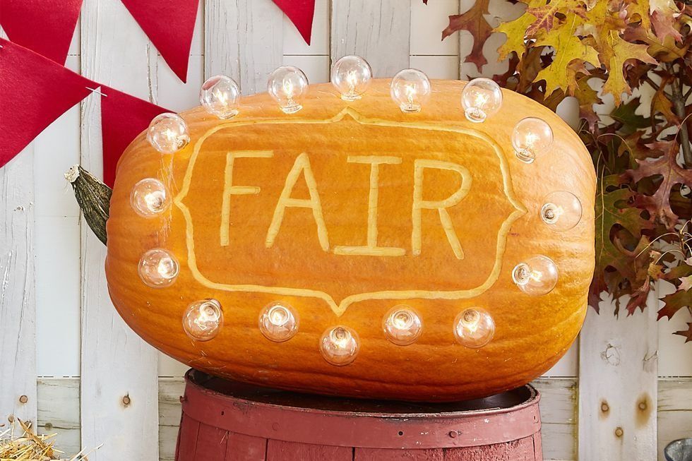 large oblong pumpkin with the word fair carved on the side, circled in lights