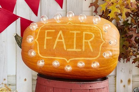 large oblong pumpkin with the word fair carved on the side, circled in lights