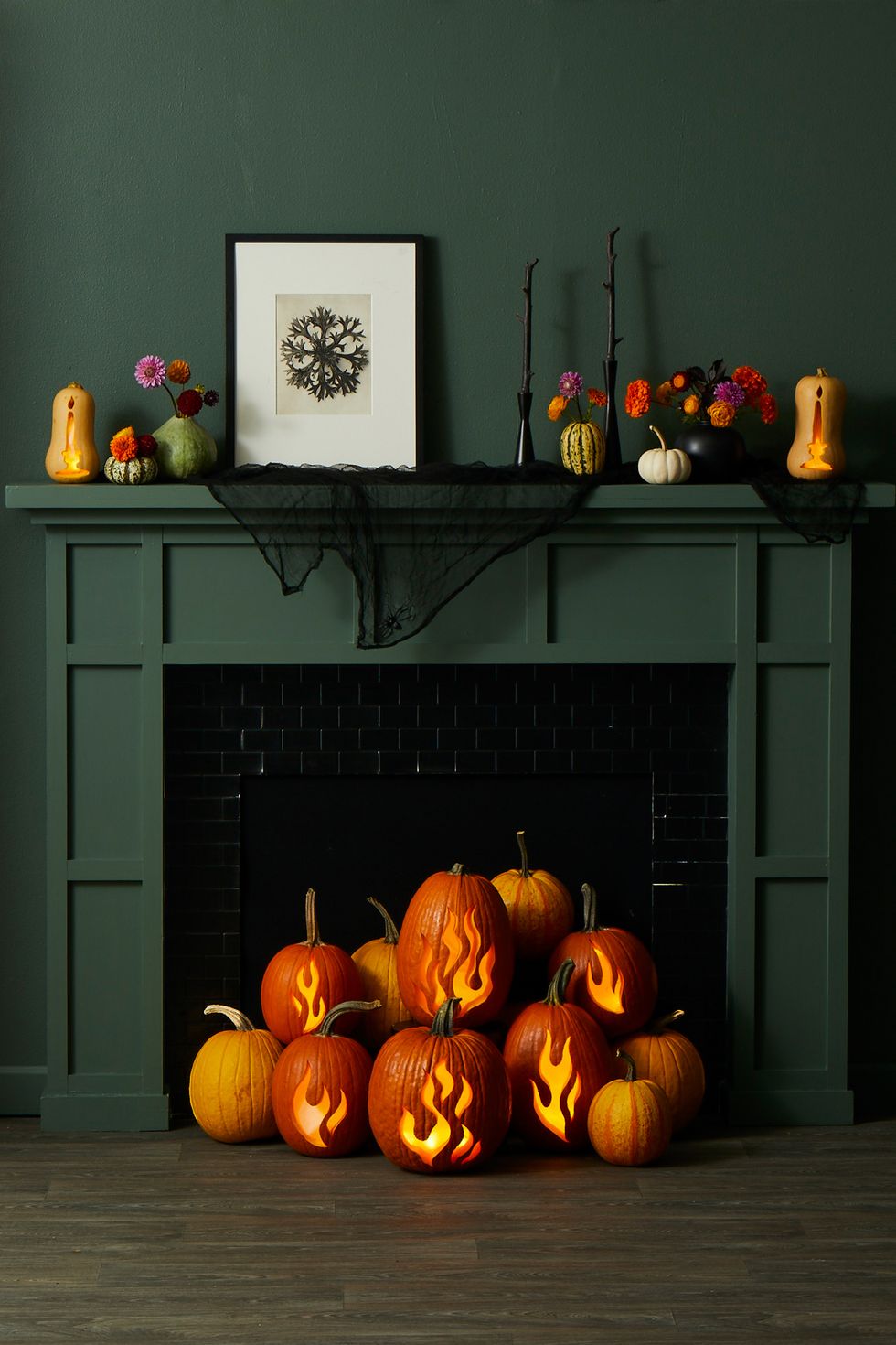 pumpkin carving ideas, multiple pumpkins with carved flamed designs in front of the fireplace