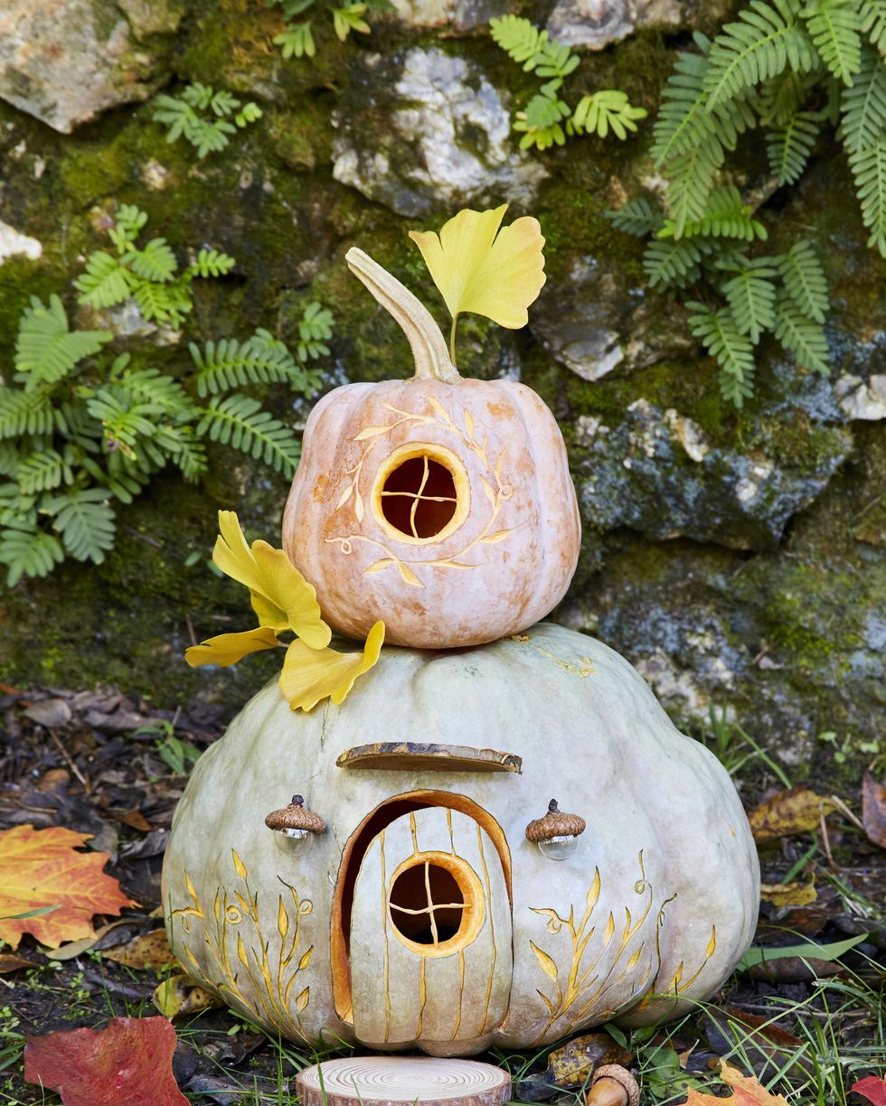 stacked pumpkin carving idea decorated to look like a gnome house with sliced wood rounds as stepping stones