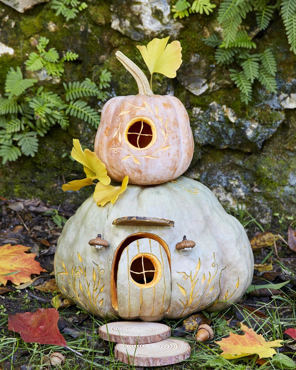 stacked pumpkin carving idea decorated to look like a gnome house with sliced wood rounds as stepping stones