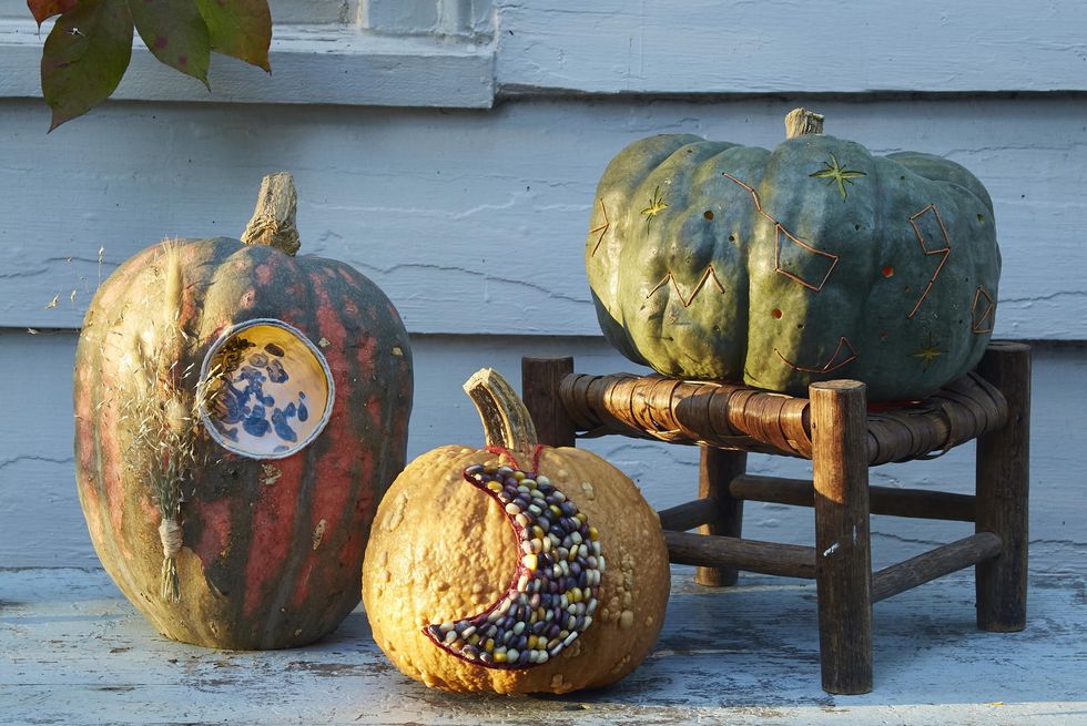 three pumpkins decorated with celestial designs and carvings