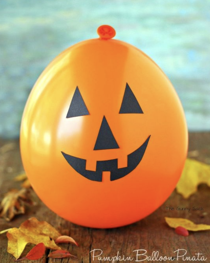 an orange balloon with a paper pumpkin face attached to the front