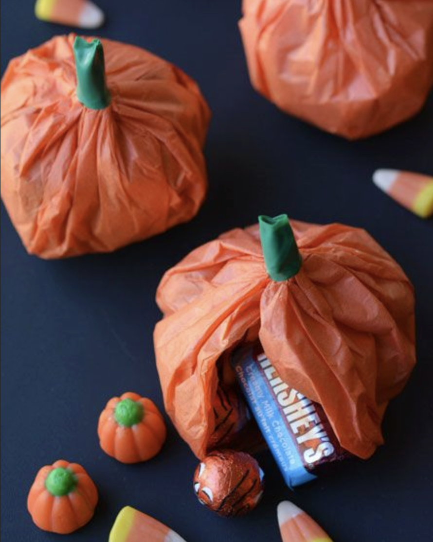 small pumpkins made from tissue paper and green tape filled with candy