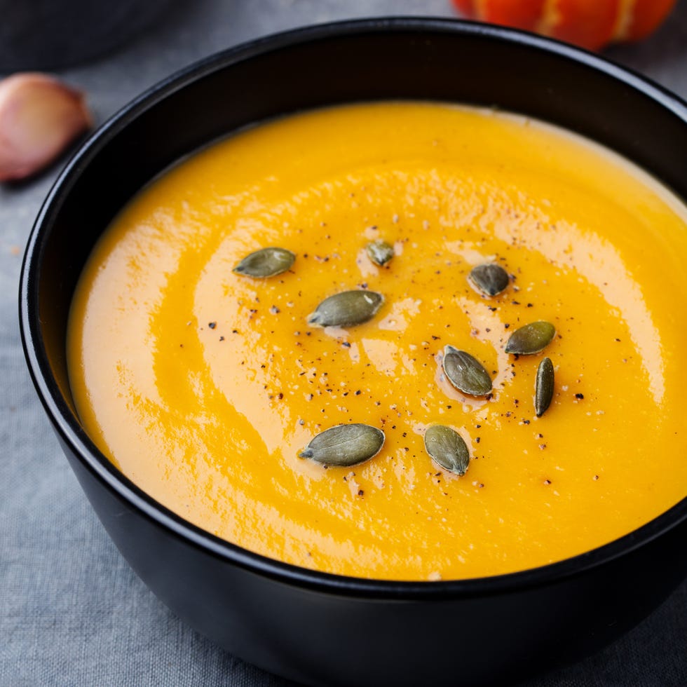 pumpkin cream soup with pumpkin seeds in a black bowl