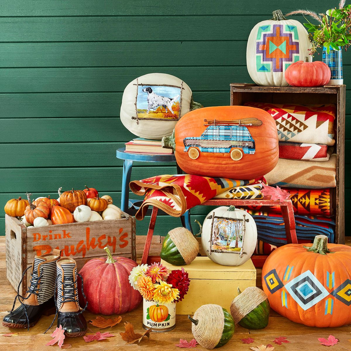 fall pumpkin display styled with mud boots, pendleton blankets, vintage crates and stools, green cabin wall backdrop