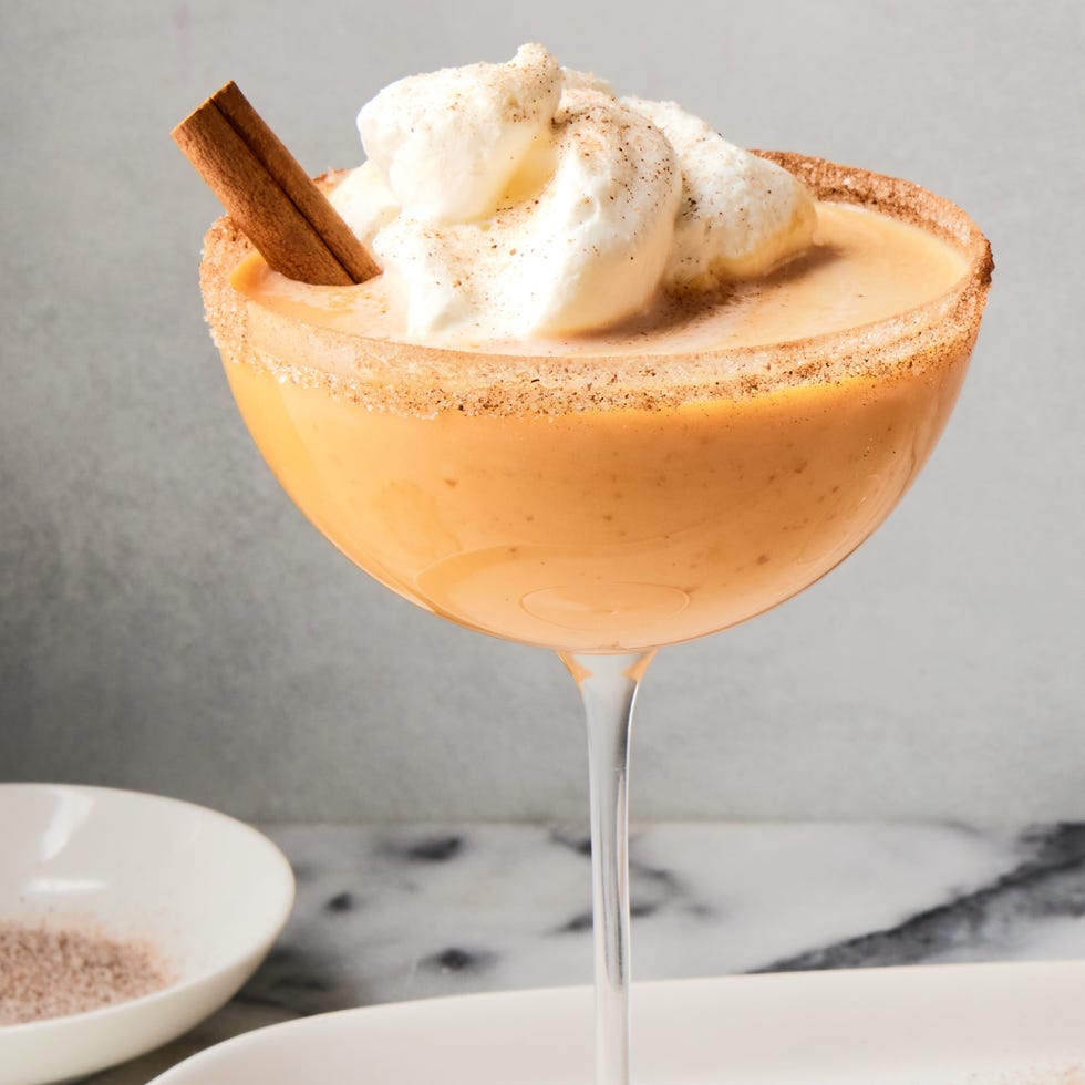 pumpkin pie martini with whipped cream and a cinnamon stick