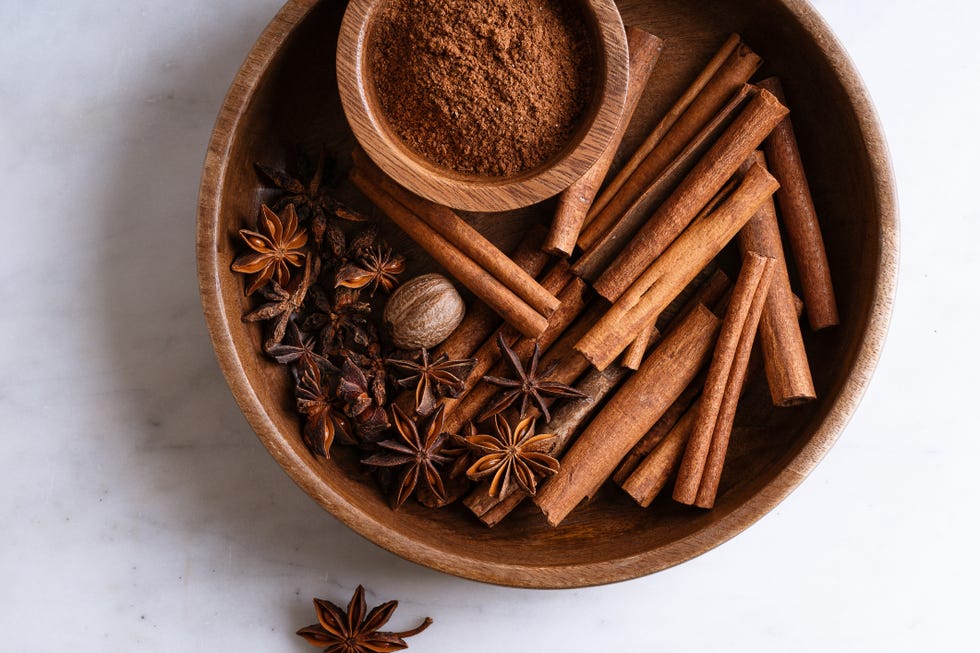 pumpkin pie spice ingredients cinnamon, nutmeg, star anise in wooden bowl