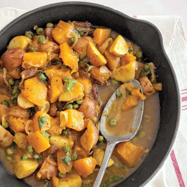 curried pumpkin and peas in an individual sized cast iron skillet with a spoon