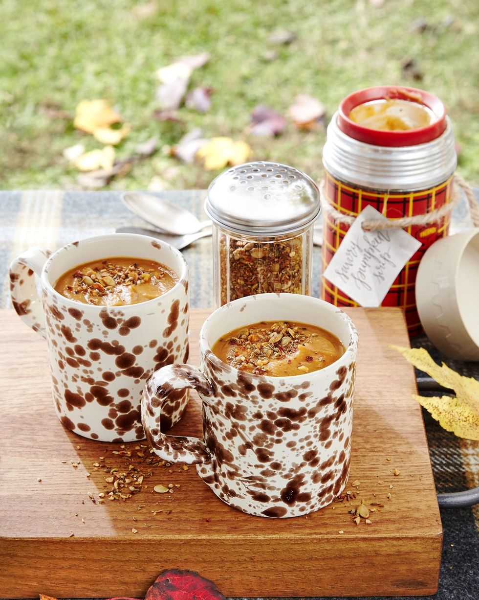 savory pumpkin soup in brown and white speckled mugs and topped with a homemade spice blend