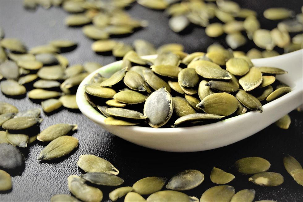 pumpkin seeds on a spoon in black background, close up