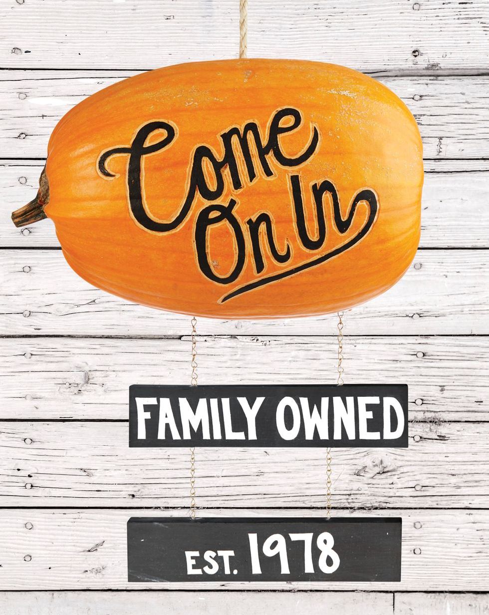 carved and painted pumpkin sign reading, come on in, with wood signs below reading family owned, est 1978